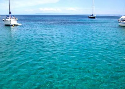 Asinara escursioni - mare Stintino con isola dell'Asinara e barche nello sfondo. Prenotazione escursioni con Asinara Sail Experience.